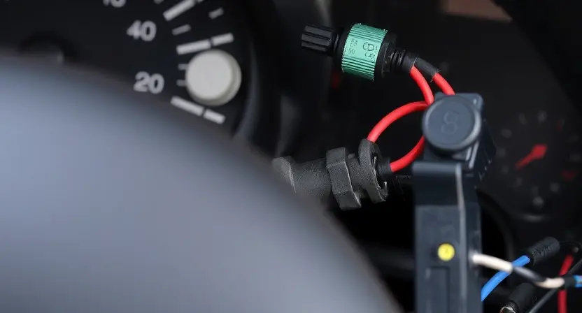 A detailed close-up of the wiring harness and instrument panel of a Peugeot 206, highlighting the area around the fuel level sensor. Focus on the electrical connections, wires, and the sensor itself. The image should convey a sense of technical inspection and repair.